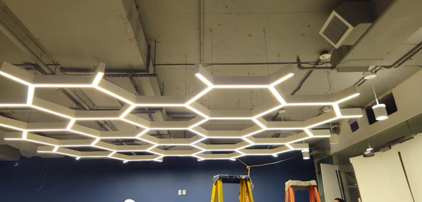 Hexagon Feature LED Grid — Statement honeycomb LED ceiling feature installed over an open commercial space — clean alignment under exposed concrete deck.